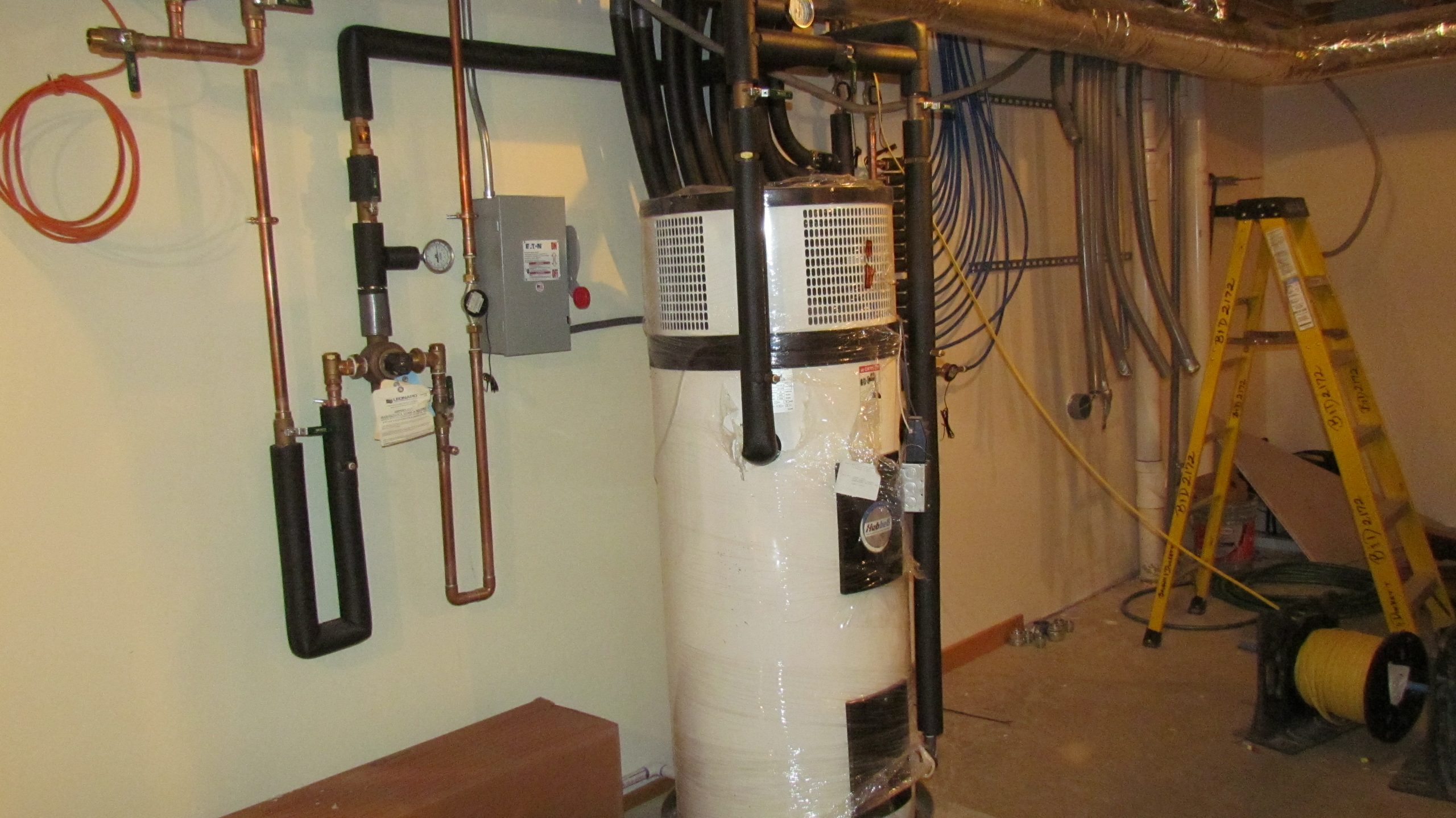 Termodynamiczny podgrzewacz wody zainstalowany w pomieszczeniu technicznym, z siecią hydrauliczną