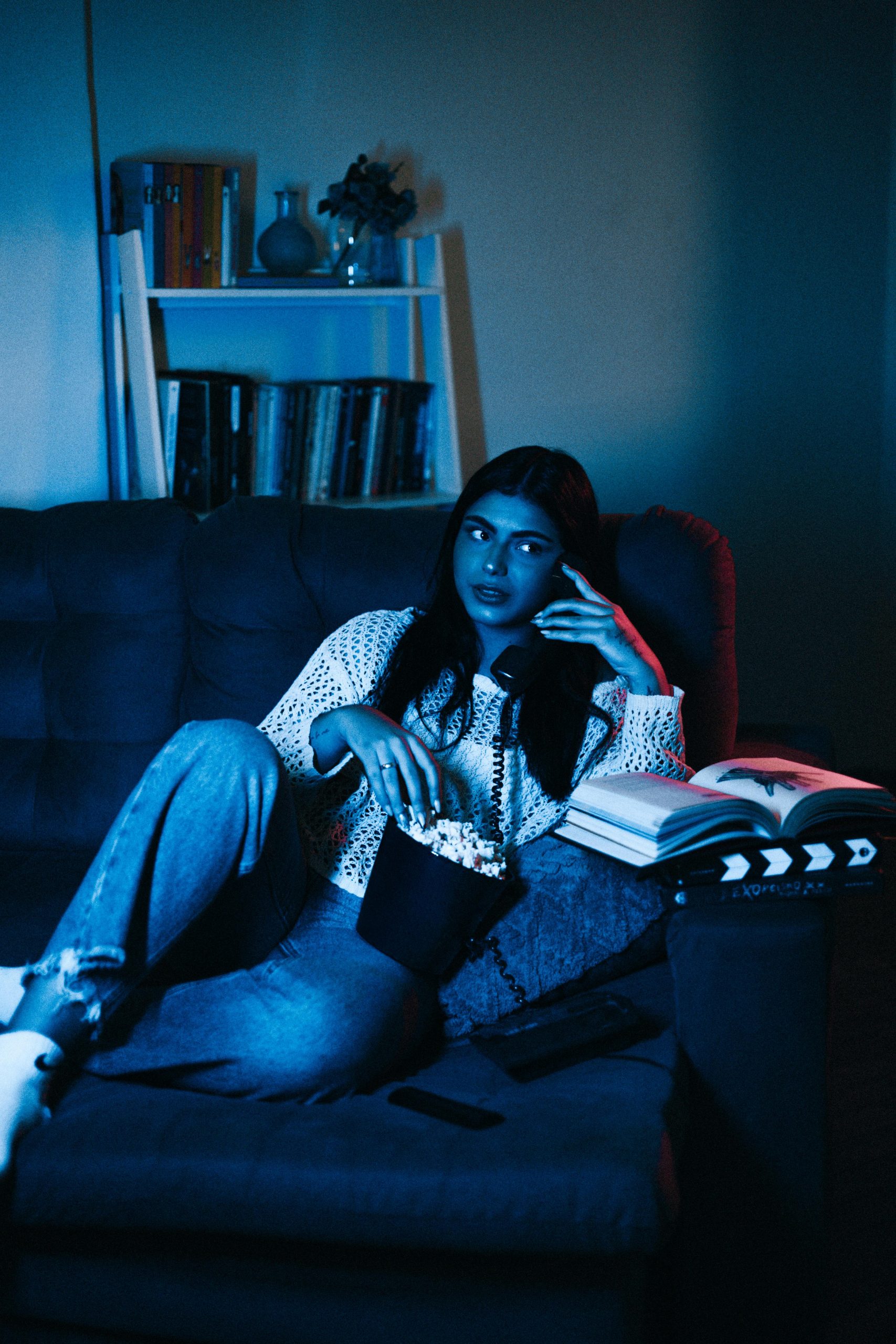 Young woman watching a movie streaming on her couch, blue light - streaming illustration