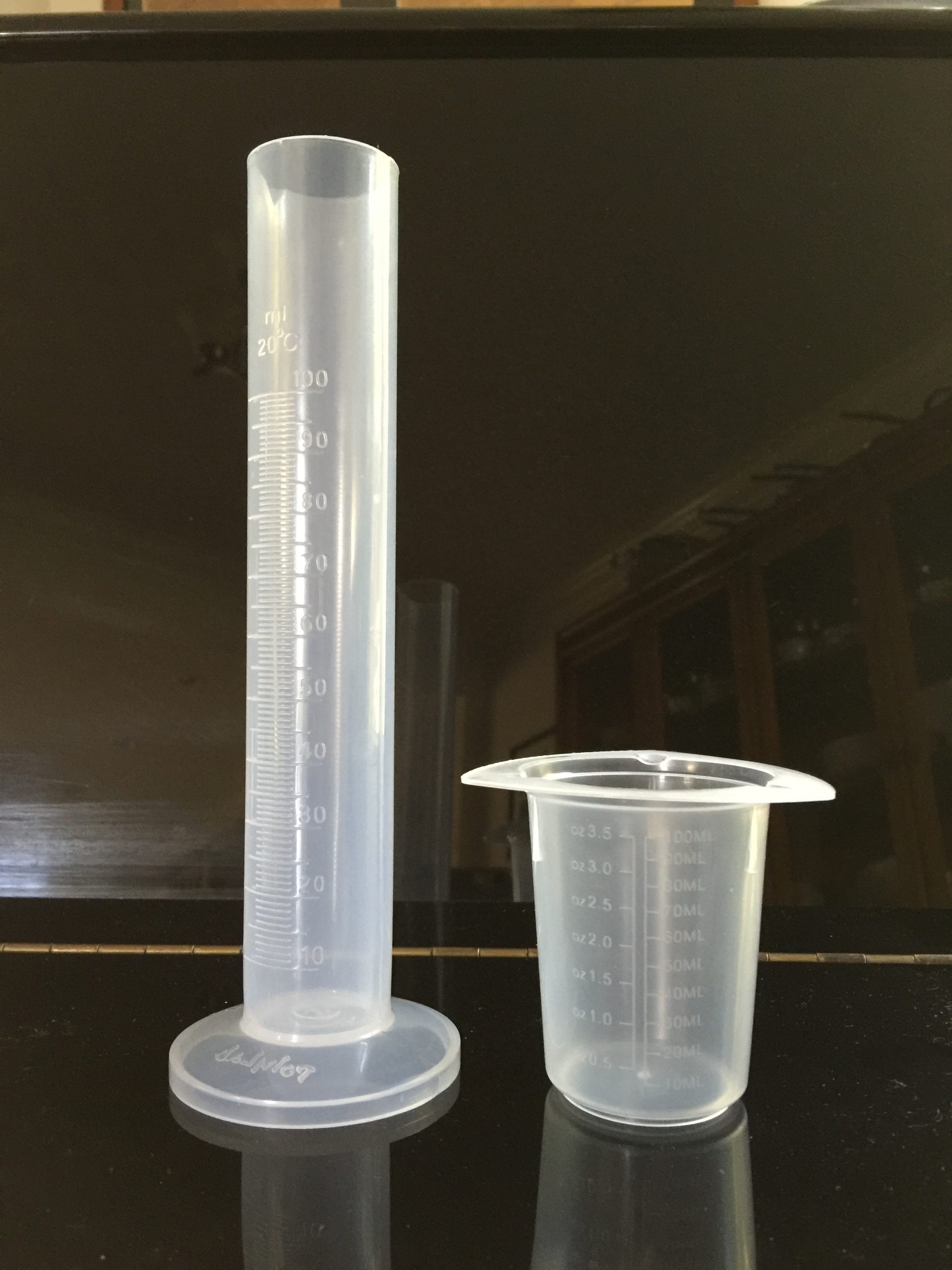 Messzylinder und Kunststoffbecher zur Messung von Volumen in Millilitern und Litern