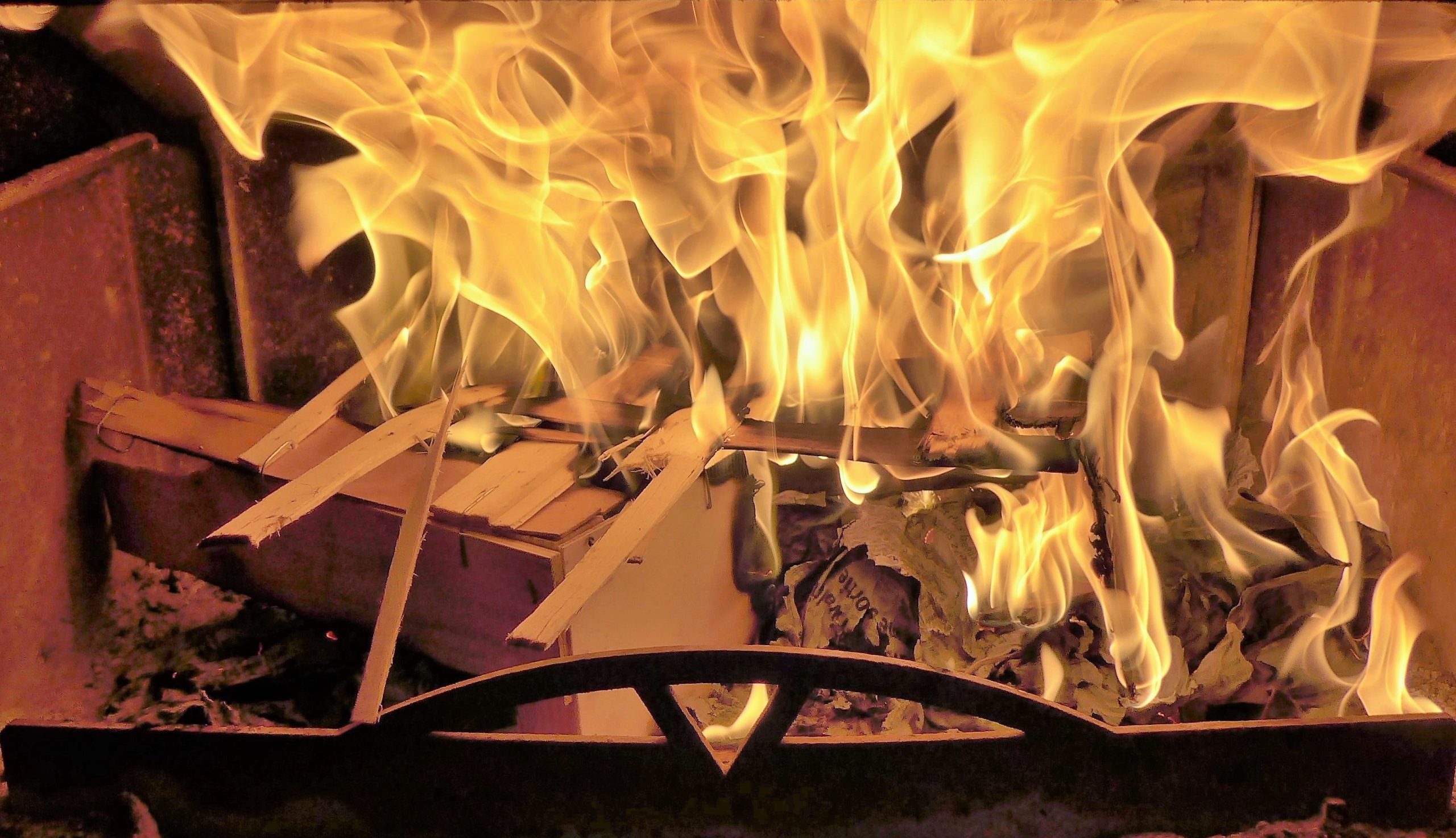 Entzünden eines Feuers in einem Holzofen mit Anzündholz und Papier